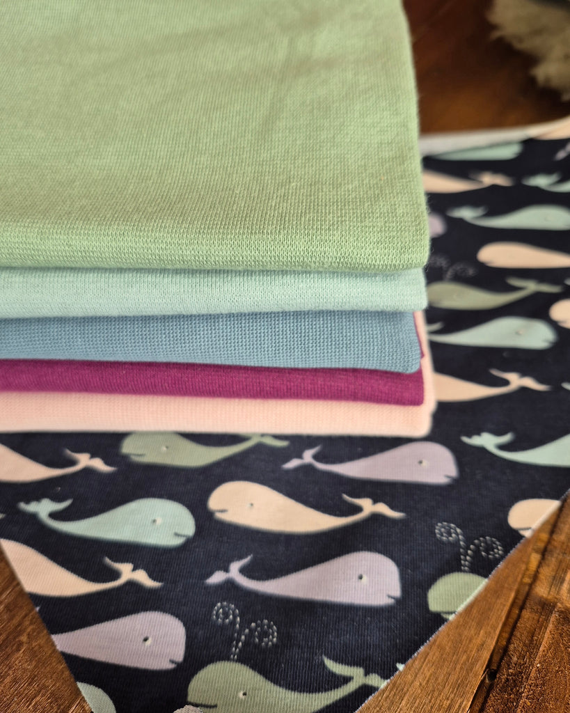 Whale Print Stack of colourful fabric swatches with whale pattern on a wooden surface