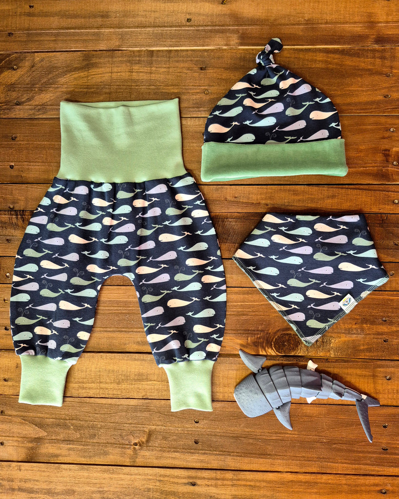 Whale Print Top Knot Hat .Baby outfit set with pants, hat, and bib on a wooden surface, Whale print