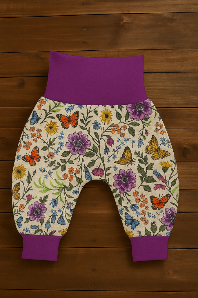 Floral-patterned baby trousers with purple accents on a wooden surface