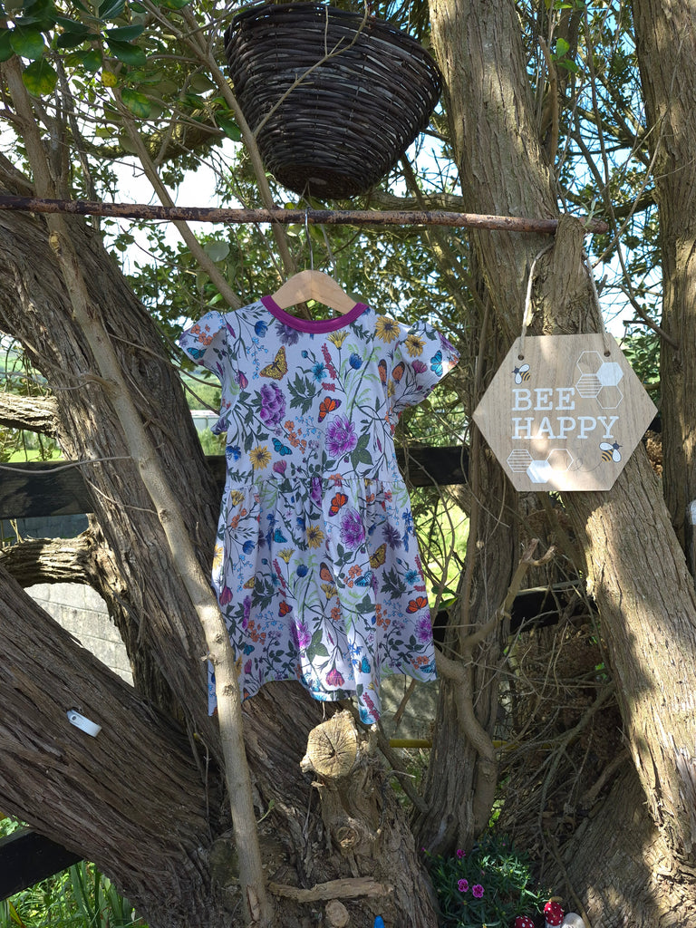 Organic cotton children's dress with hand-drawn wildflower print, flutter sleeves, and knee-length design by Cake & Elf